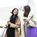 two happy beautiful girls shopping in the city with shopping bags and cup of coffee - fashion and