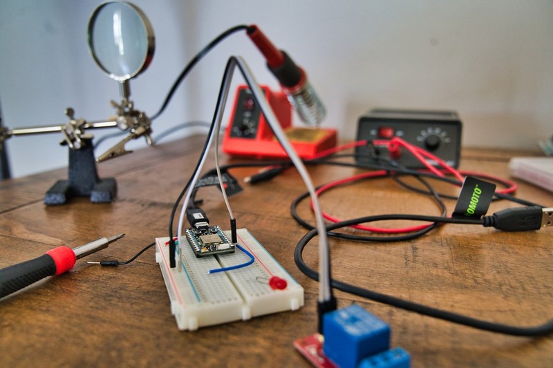 Digital calipers and a multimeter on a desk next to a 3D printer