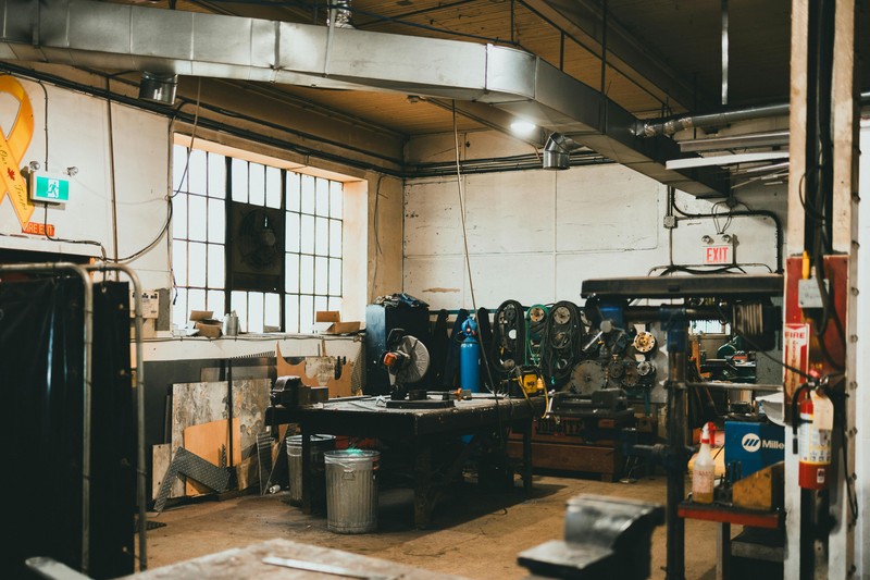Two spools of 3D printer filament, one Polymaker ASA and one Hatchbox ABS, on a shelf in a workshop