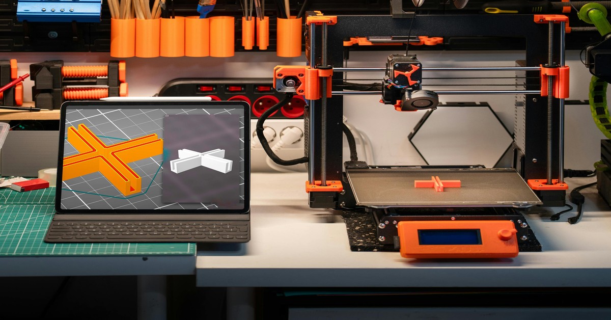 A budget 3D printer under $300 sitting on a desk with a filament spool loaded and a small printed object nearby.