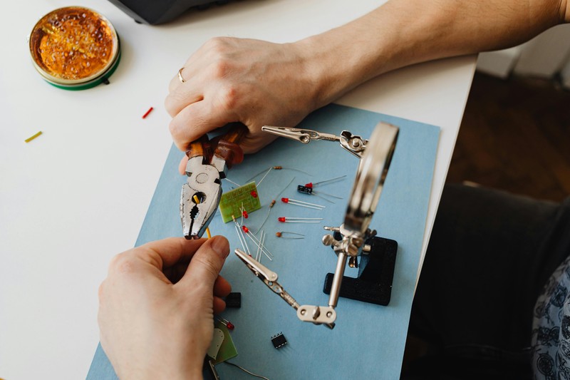 A hand spray priming a miniature model with matte primer in a well-lit workspace